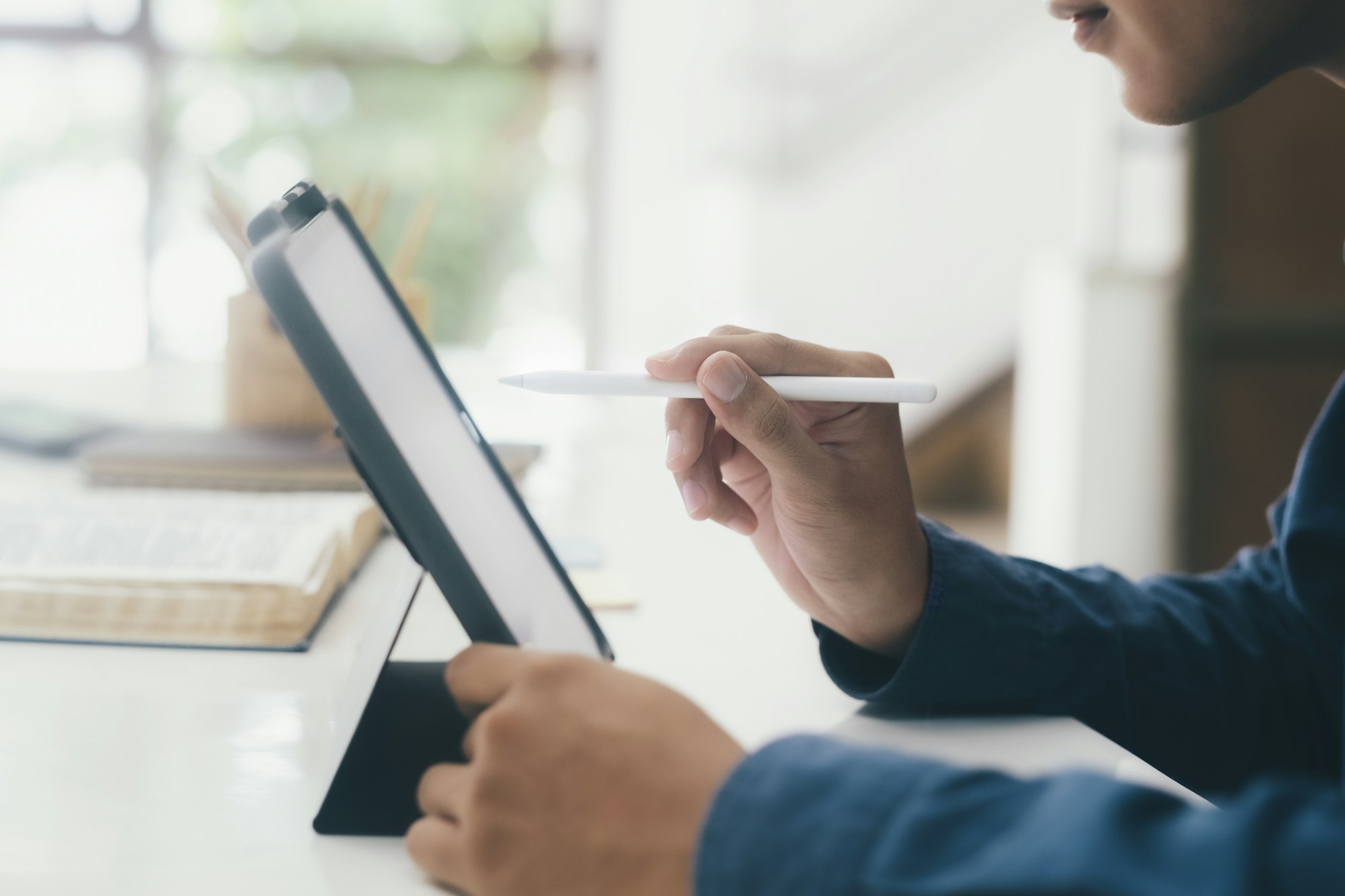 Casual business man with stylus pen writing on digital notepad.