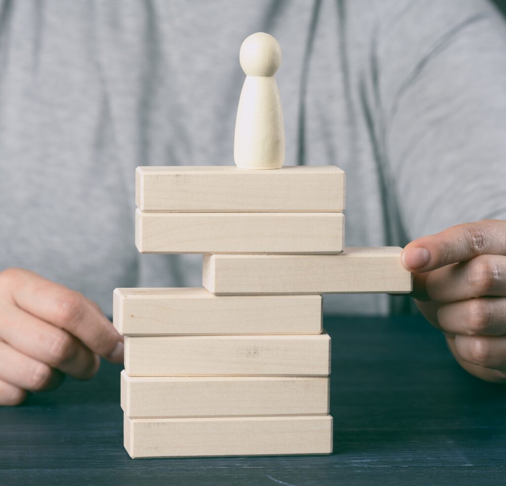 Woman's hand pulls out a wooden block from the tower on which the figurine stands